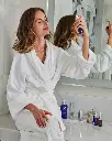 Copper Firming Mist de la marca Is Clinical: Mujer aplicando el producto con otros productos de la marca