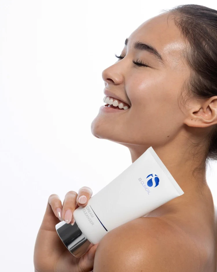 Cream Cleanser de la marca Is Clinical: Mujer sonriendo mostrando el producto