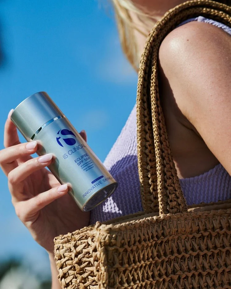 ECLIPSE SPF 50+ de la marca Is Clinical: Mujer con bolso mostrando el producto