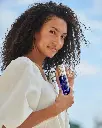 Copper Firming Mist de la marca Is Clinical: Mujer mostrando el producto para apreciar el tamaño